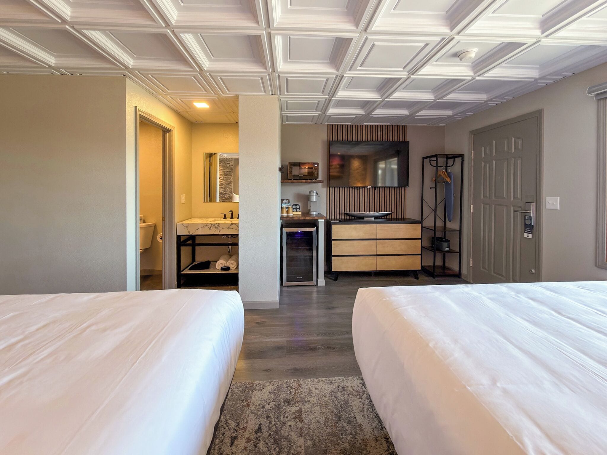 Habitación de hotel con dos camas, un baño con tocador, microondas y televisión.