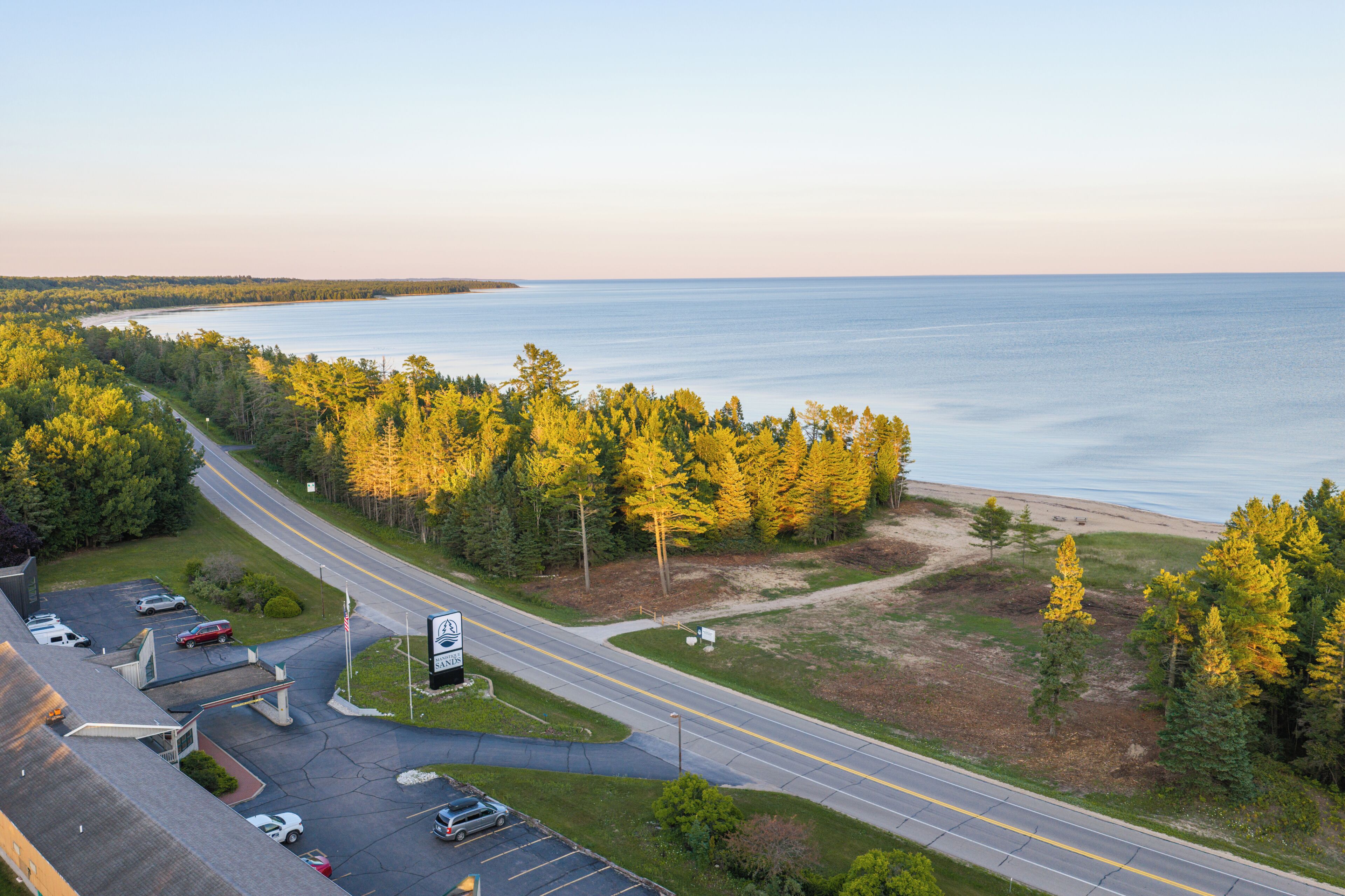 A coastal road with a parking lot and a beach in the background.