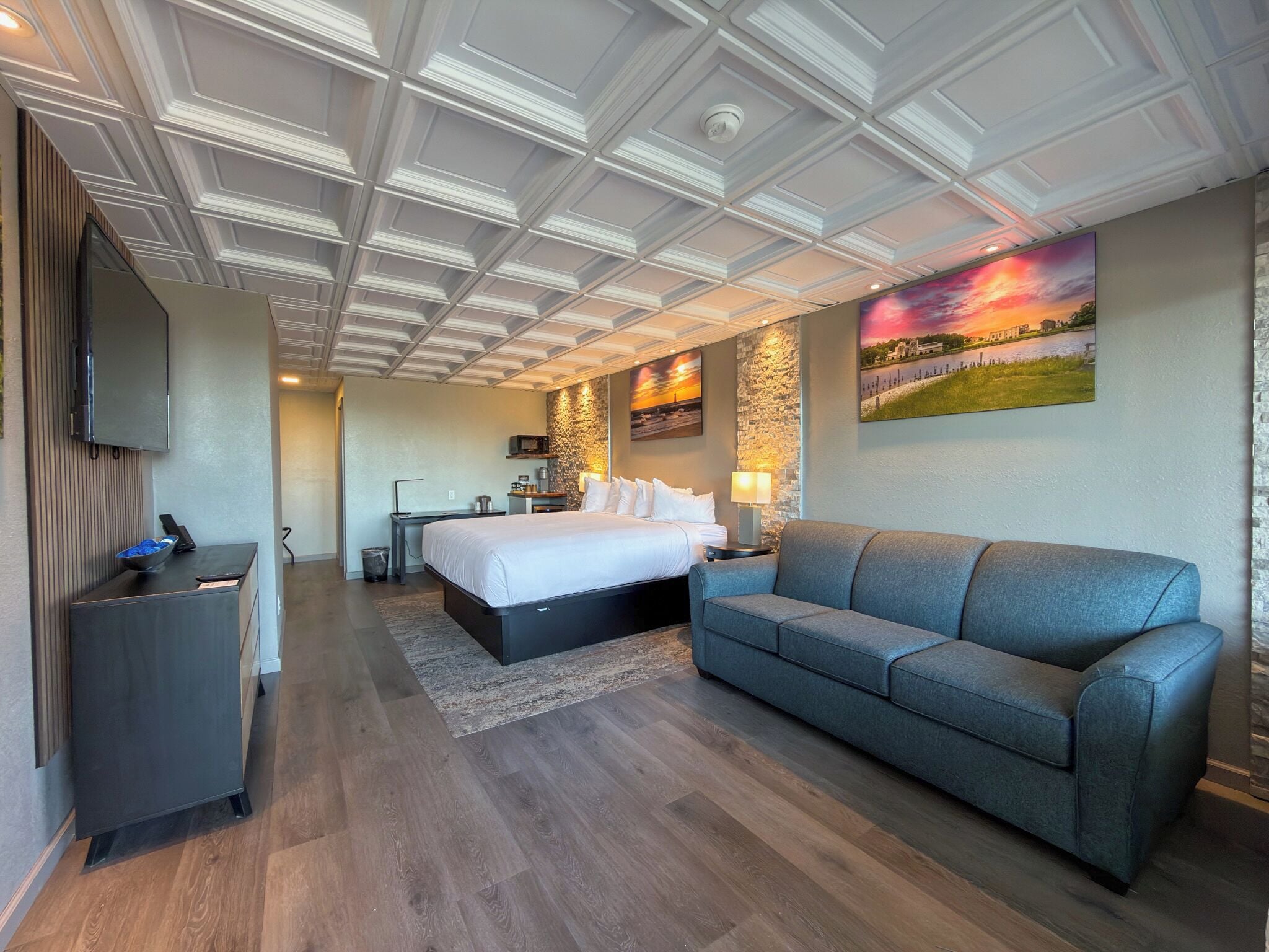 A hotel room with a bed, a sofa, a desk, and a TV.