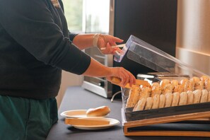 Una persona sirviendo pan de una vitrina.