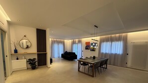 Una sala de estar moderna con comedor, un sofá negro y una mesa de comedor con sillas.
