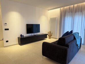A modern living room with a flat-screen TV, dark sofa, and a minimalist design. - Elegant Apartment in the Center of Palermo, Notarbartolo Design Apartment (Palermo)