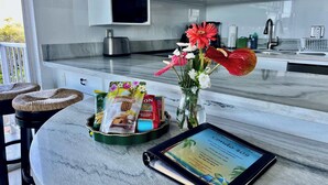 Eine Küche mit weißen Schränken, einer Mikrowelle, einer Kaffeemaschine und einem Tablet, das eine Willkommensbotschaft anzeigt.