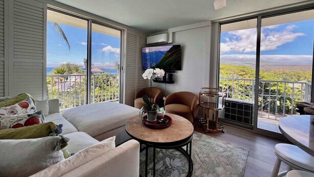 Ein geräumiges Wohnzimmer mit großem Fernseher, bequemen Sitzgelegenheiten und einem Balkon mit herrlicher Aussicht.
