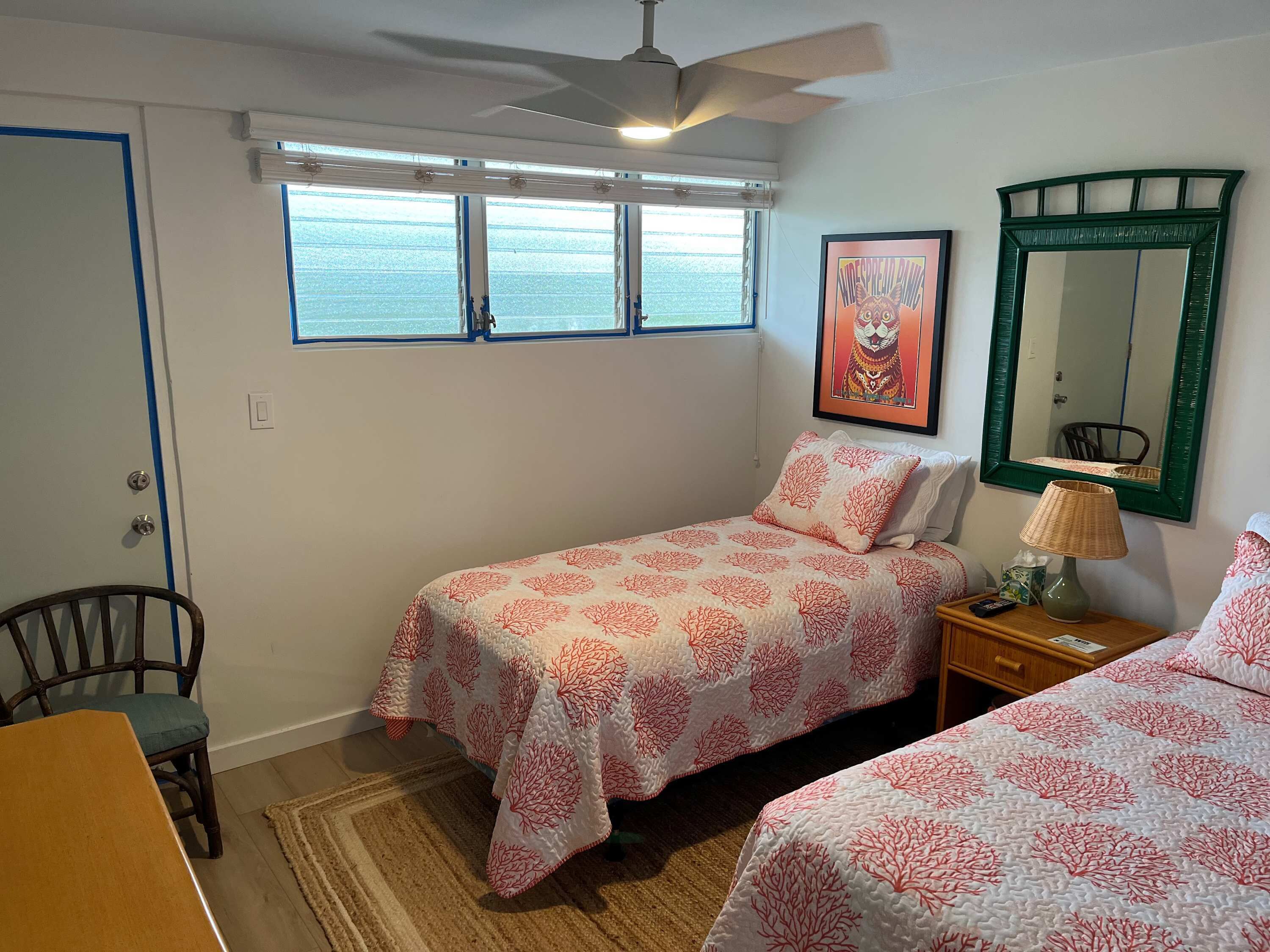 A bedroom with two beds, a chair, a table, a lamp, and a window with a view.