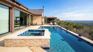 A modern house with a swimming pool, a patio with outdoor furniture, and a view of the landscape. - La Cresta: Hill Country Retreat with Heatable Pool, Fitness Room & Views (Helotes)