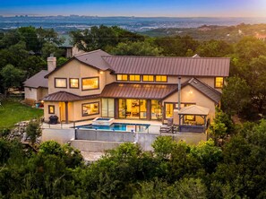 Una casa grande y moderna con piscina, varias habitaciones y vista a la ciudad.