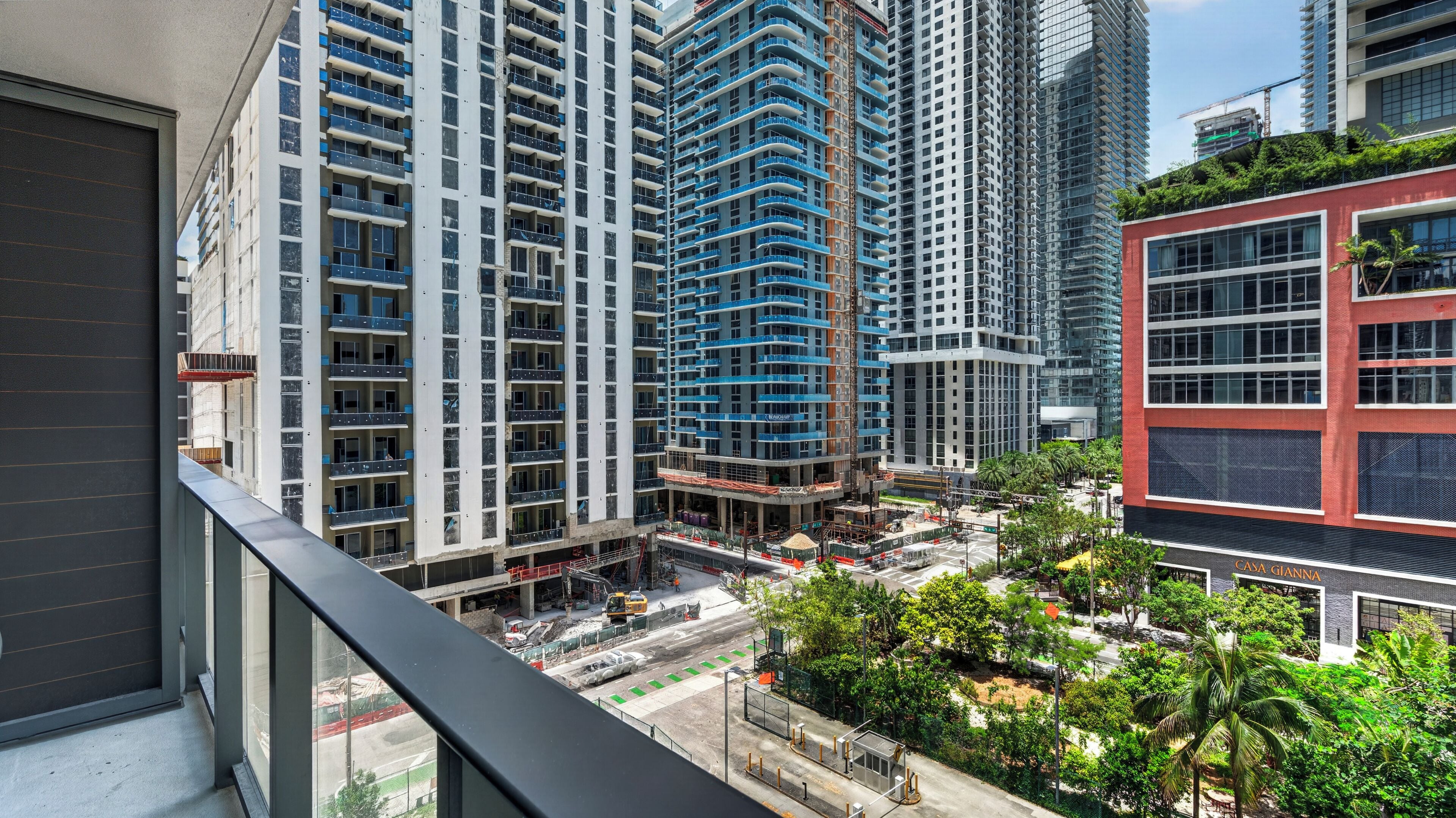 A high-rise building with multiple balconies, a construction site in the foreground, and a red building with a sign 'CASA GIANNELLA' in the background.