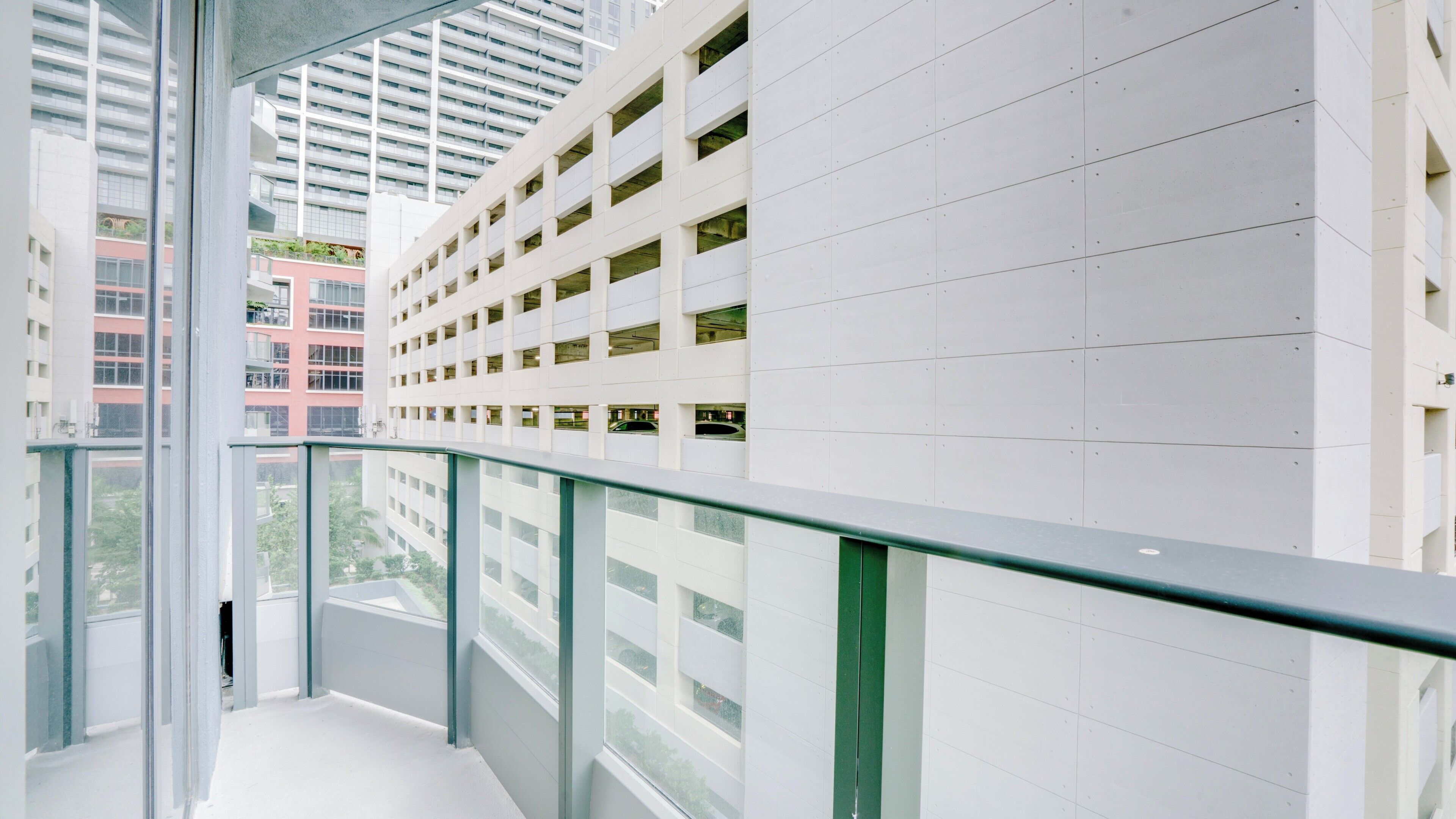 A modern building with a glass balcony, white walls, and multiple windows.