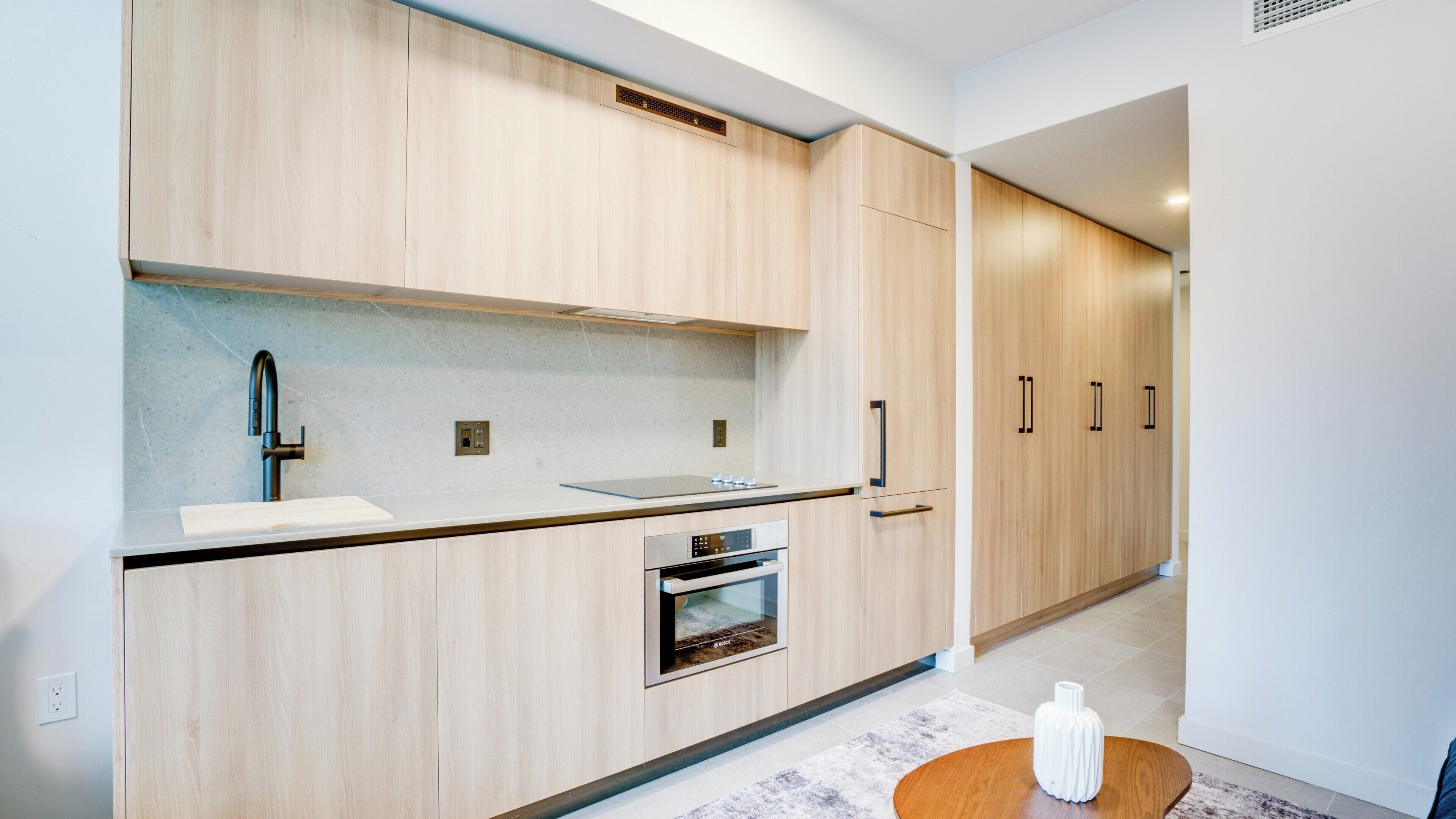 A modern kitchen with wooden cabinets, a built-in oven, and a countertop.