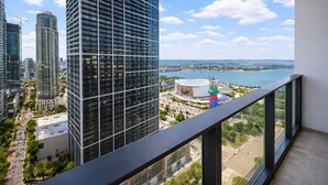 A high-rise building with a view of a body of water and a colorful tower in the distance. - The Urban Suites - 501 First Residence (Miami)