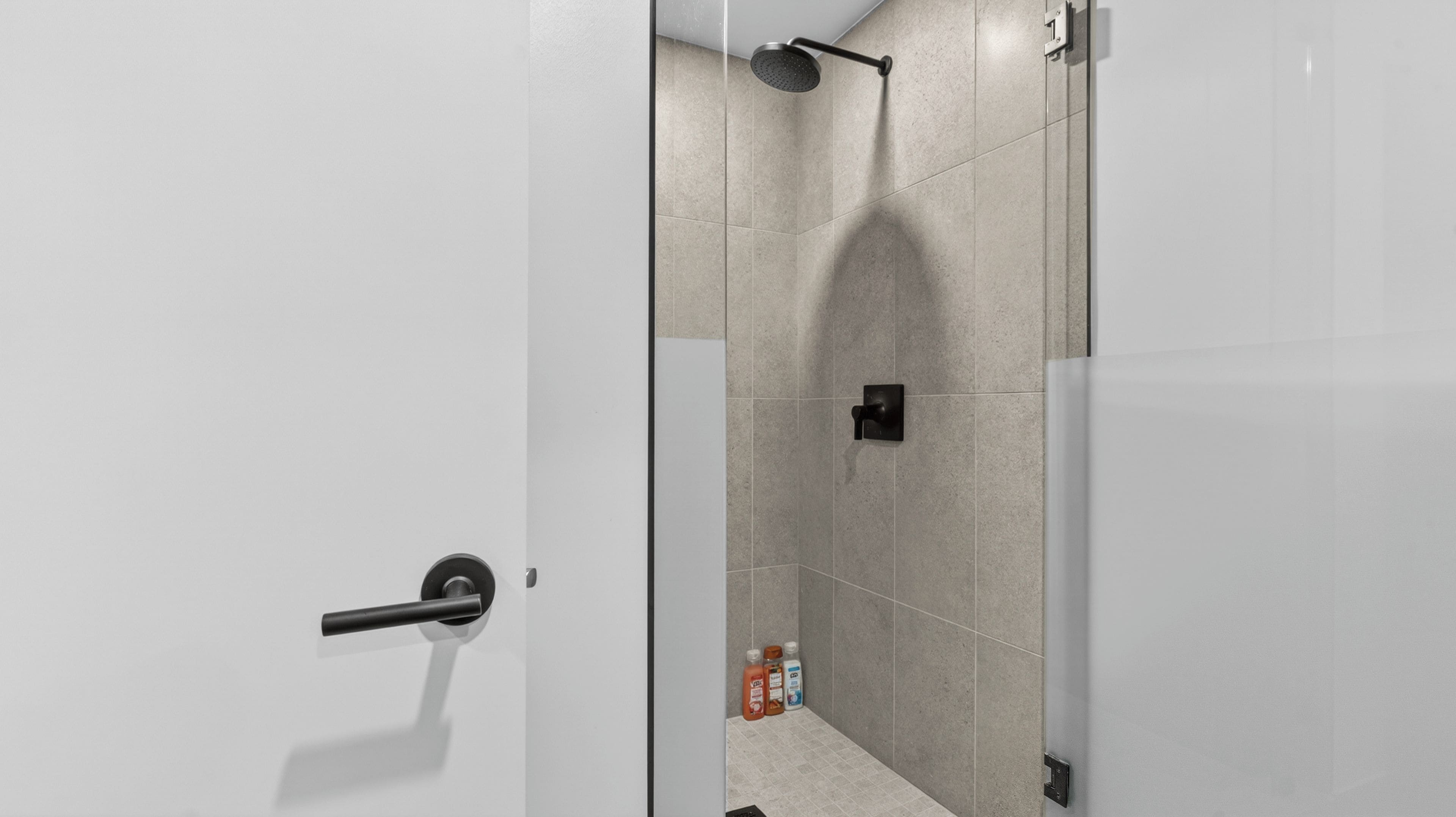 Een moderne badkamer met een douche, toilet en wastafel.