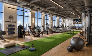 Una palestra con attrezzature per esercizi, un manto in erba sintetica verde e vista sulla città.