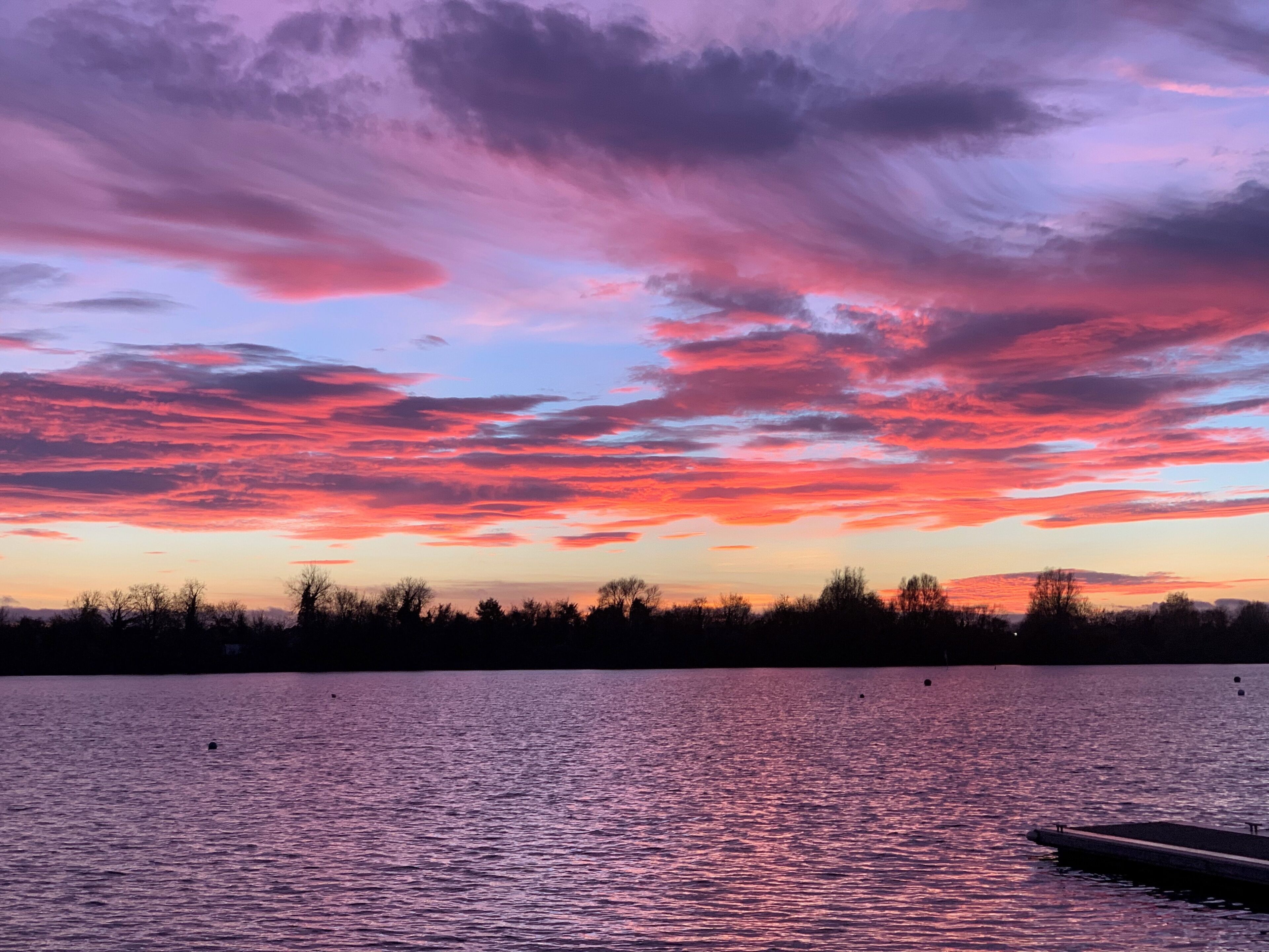 A sunset over a body of water with a dock.