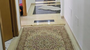 Ein Flur mit einem gemusterten Teppich, ein Essbereich mit Stühlen und einem Tisch sowie ein Gemälde an der Wand.