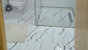 Ein Badezimmer mit Duschkabine aus Glas, Toilette und Waschbecken mit Spiegel darüber.