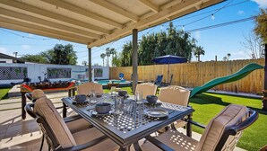 An outdoor patio with a covered table, chairs, and a slide. - 4BR Oasis w/pool, Cold Plunge, Gym, Game Room (Phoenix)