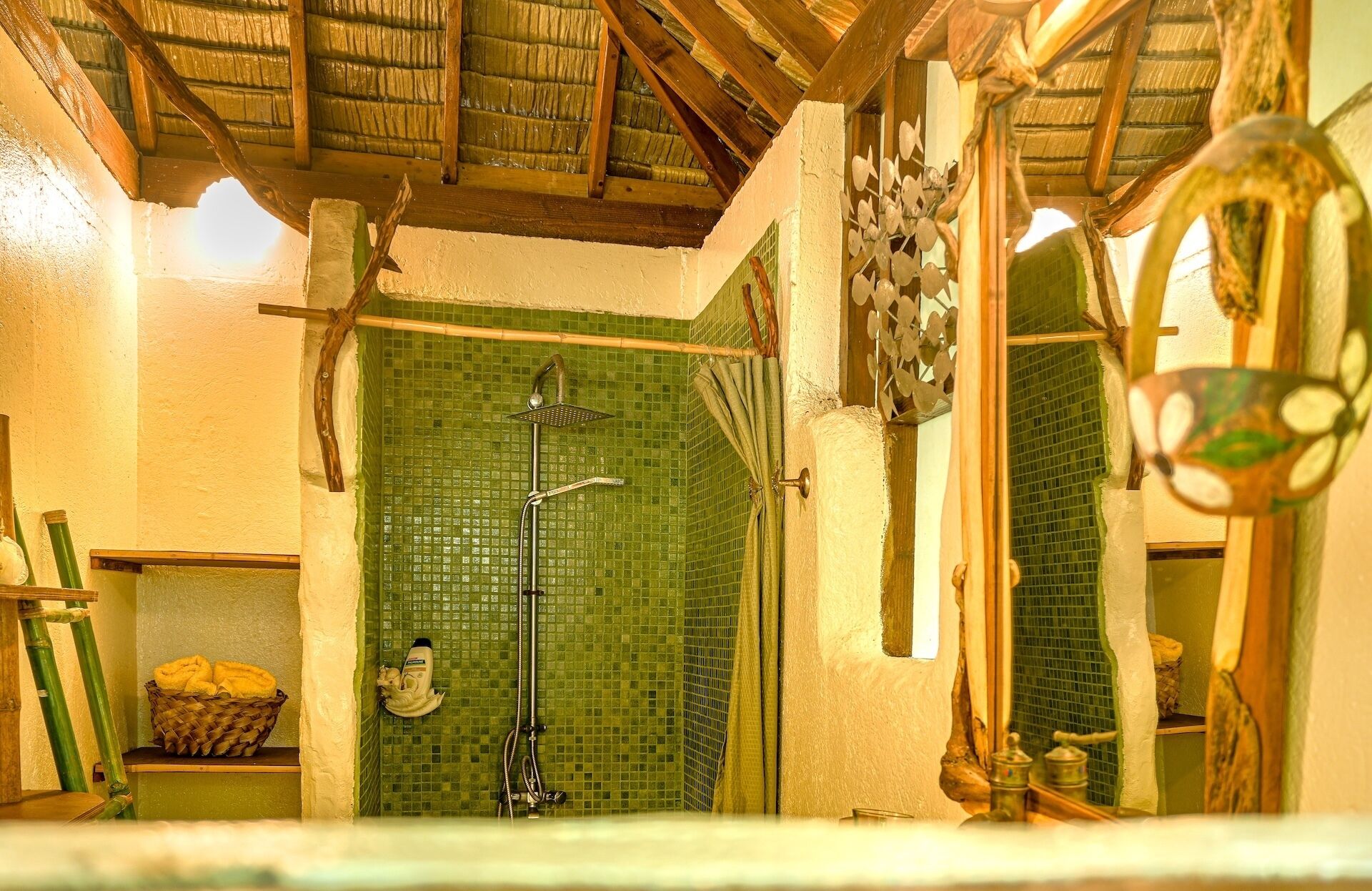 Ein Badezimmer mit grüner Mosaikwand, einer Dusche inklusive Handbrause und einer Holzbalkendecke.