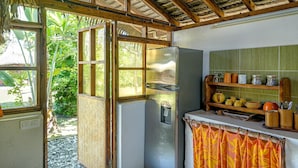 Une cuisine compacte dotée d’un réfrigérateur encastré, d’une fenêtre avec un cadre en bois et d’une étagère contenant des ustensiles de cuisine.