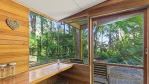 A wooden interior with large windows, a heart-shaped decoration, and a bench.