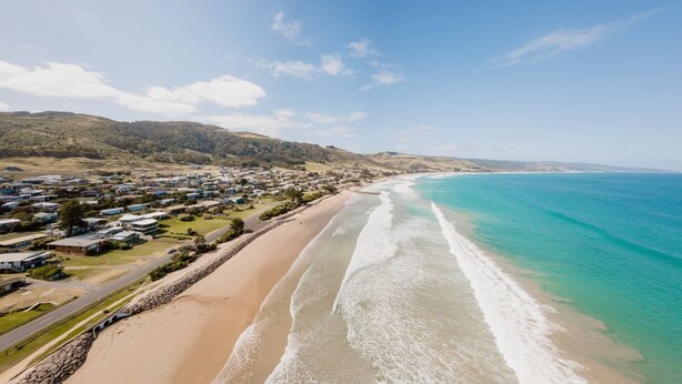 A coastal town with a beach, houses, and a clear sky.