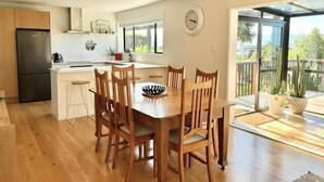 A modern kitchen with a refrigerator, white cabinets, and a dining area with wooden chairs and a table.