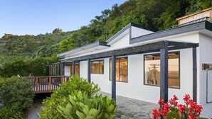 A modern house with a stone pathway, a wooden deck, and lush greenery.