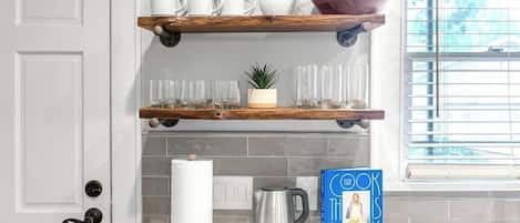 Una cocina con gabinetes blancos, una cafetera, un hervidor y un libro titulado 'The Book Is Molly'.