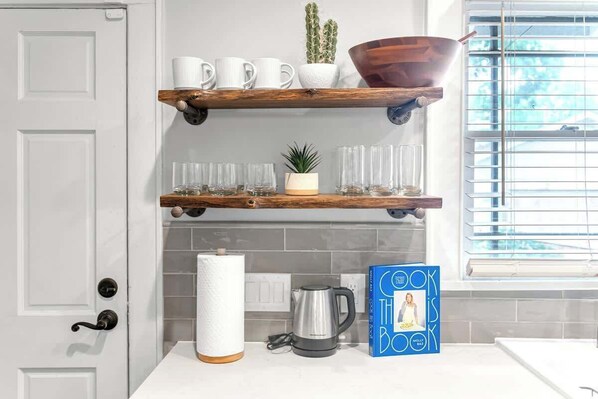 A kitchen with white cabinets, a coffee maker, a kettle, and a book titled 'The Book Is Molly.' - Honky Tonk Heights | 2 Kings, Fire Pit, EV Charger (Houston)