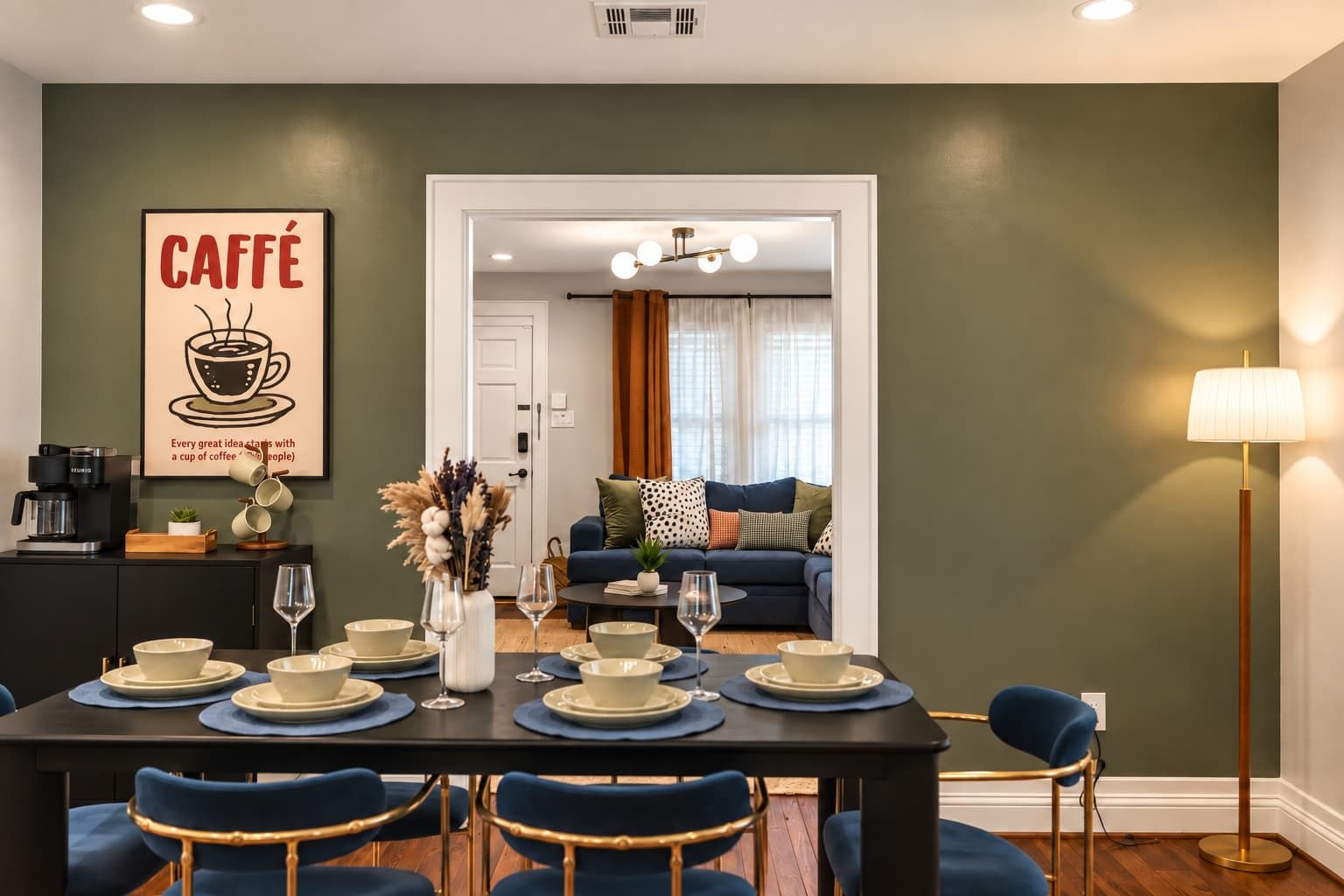 A dining area with a table set for four, a coffee machine, and a wall art piece.