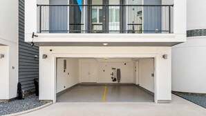 A modern building with a covered parking area, a balcony with a railing, and a door with a handle. - Montrose Rooftop Townhome | 3 Suites, Sleeps 8 (Houston)