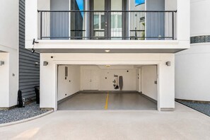 Ein modernes Gebäude mit überdachtem Parkplatz, einem Balkon mit Geländer und einer Tür mit Griff.