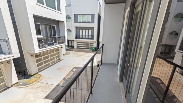 A multi-story residential building with balconies, a garage, and a concrete pathway.