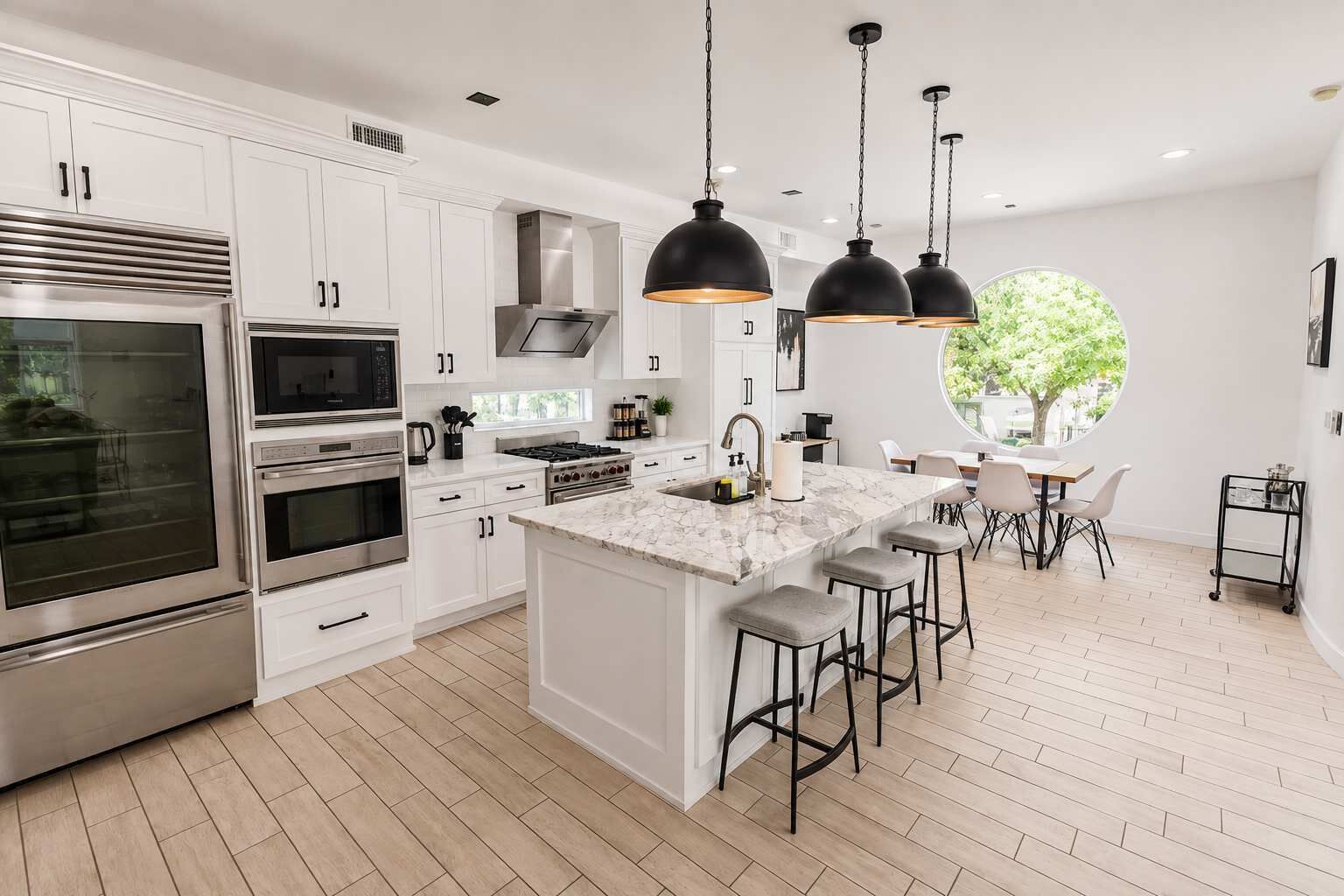 A modern kitchen with white cabinetry, stainless steel appliances, a marble island, and pendant lighting.