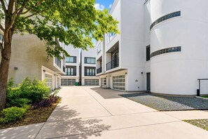 A modern building with a central courtyard, garage doors, and a tree.