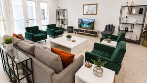 A modern living room with a sofa, armchairs, a coffee table, and a TV.