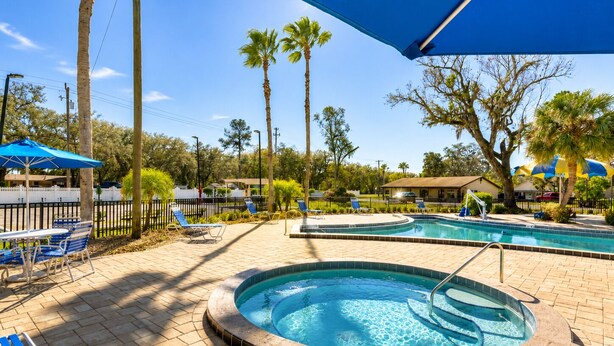 Un espace piscine comprenant un jacuzzi, des chaises longues et des parasols.