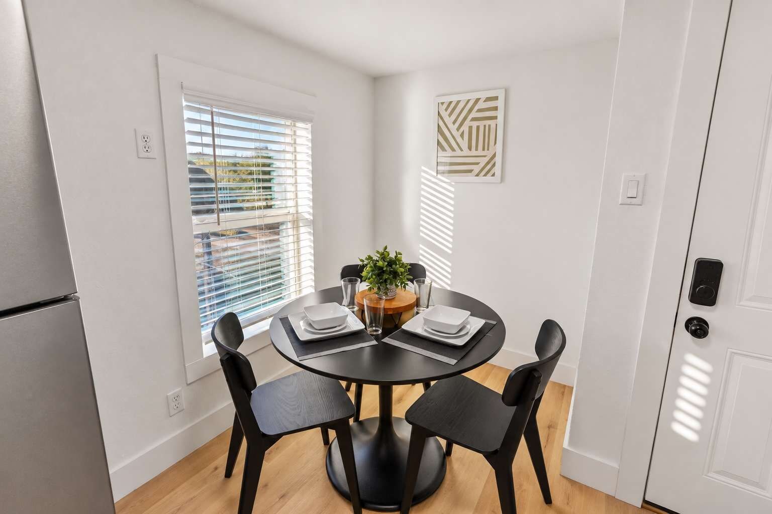 A dining area with a round table, four chairs, and a small plant.