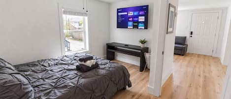 A bedroom with a bed, a desk, a TV, and a ceiling fan.