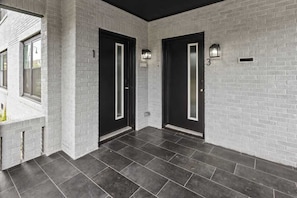 A modern building with white brick walls, dark tiled floors, and black doors with illuminated panels. - 2BR Loft Near TSU + Med Center | In-Unit Laundry | Third Ward Houston 1 (Houston)