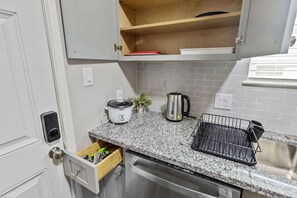 A kitchen with granite countertops, a built-in oven, a coffee maker, and a dish rack. - Historic 2BR Loft 2 I Med Center I NRG I Downtown (Houston)