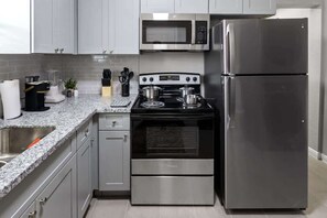 Une cuisine équipée d’un réfrigérateur en acier inoxydable, d’un four à micro-ondes, d’une cuisinière et d’un évier.
