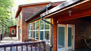 A wooden cabin with a deck, large windows, and a door. - Spacious, Inviting, and Beautiful 4 Bedroom Home (Fairbanks)