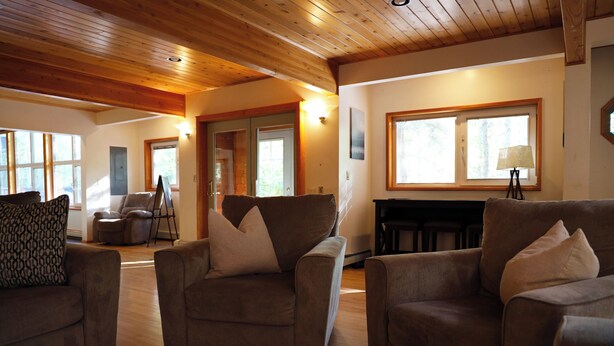 A spacious living room with wooden ceilings, large windows, and a fireplace. - Spacious, Inviting, and Beautiful 4 Bedroom Home (Fairbanks)