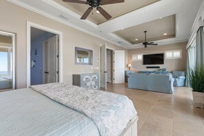A bedroom with a bed, a dresser, a TV, and a seating area with a sofa and a chair.