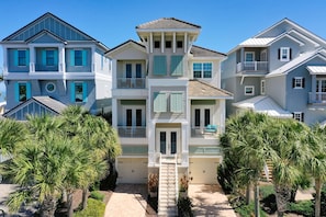 A multi-story residential building with a central entrance, balconies, and a covered walkway.