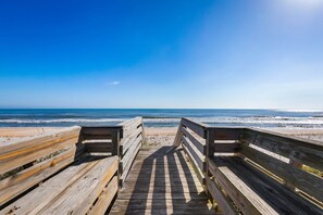 A wooden boardwalk leading to a beach with clear skies.