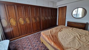 A bedroom with a large wardrobe, a round mirror, and patterned floor tiles. - 114m² 3 Bedroom Apartment With Balcony Lift and AC (Nules)