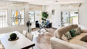 Un vaste espace de vie comprenant une table à manger en verre, un canapé et un ventilateur.