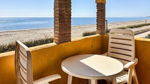 Un balcon avec une table et des chaises, donnant sur une plage.